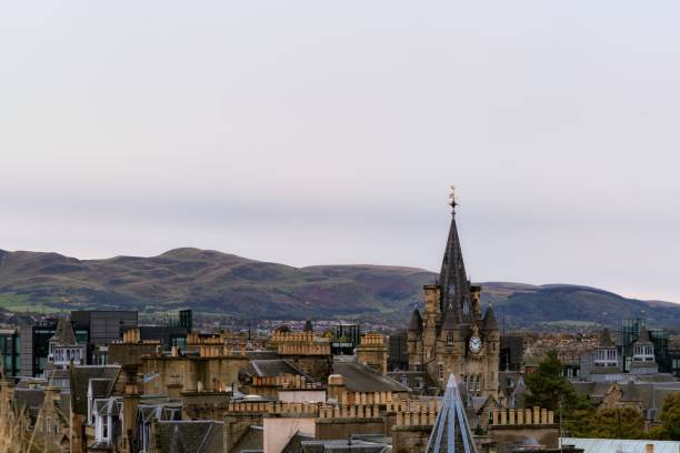 istock View of Edinburgh's historic skyline with the clock tower against rolling hills under a cloudy sky. 2200164895