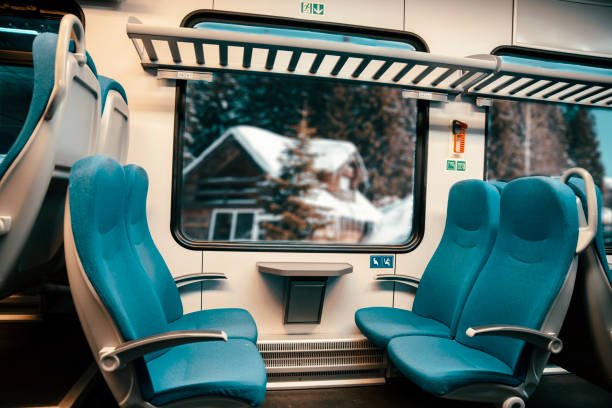 Blue empty Seats in the intercity train. Comfort Seating arrangements for commuters and travellers. Vie out window on Winter mountain houses