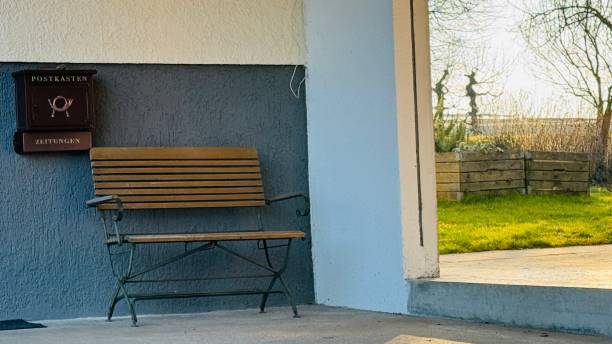 istock Wooden bench at a grey wall and view into a garden 2200166161