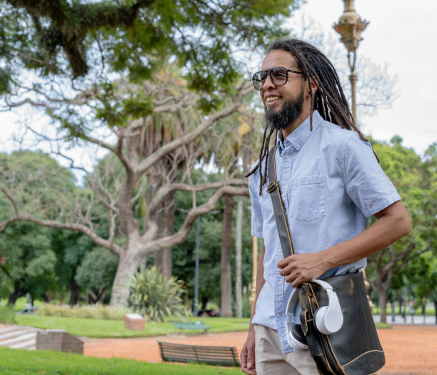 istock young latino man with dreadlocks walks to work through the park 2200169803