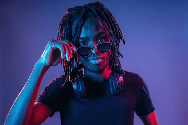 istock Touching sunglasses, front view. African American guy is studio with neon lighting 2200172409