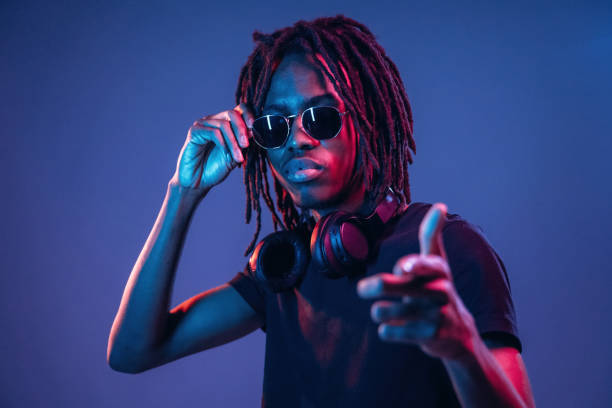 istock Pointing by finger, in sunglasses. African American guy is studio with neon lighting 2200172476