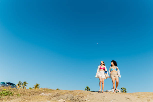 istock Young friends women talking and walking through the beach 2200179520