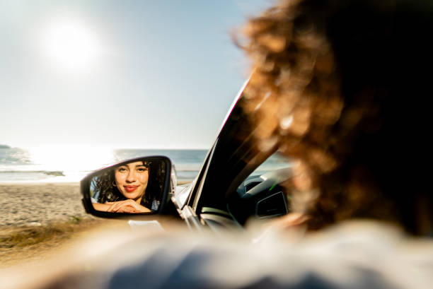 istock Young woman looking on car rear view during road trip 2200179800