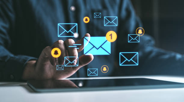 istock Digital notifications and email icons floating above a tablet screen with a hand interacting with them. 2200181657