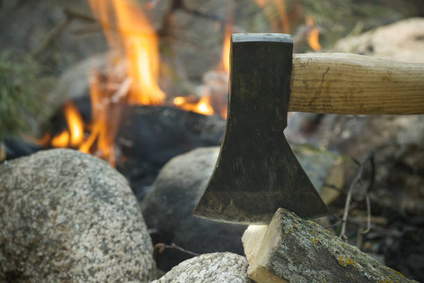 istock Axe splitting firewood near burning campfire outdoors 2200181776