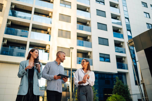 Real estate agents discussing business strategy holding digital tablet outside