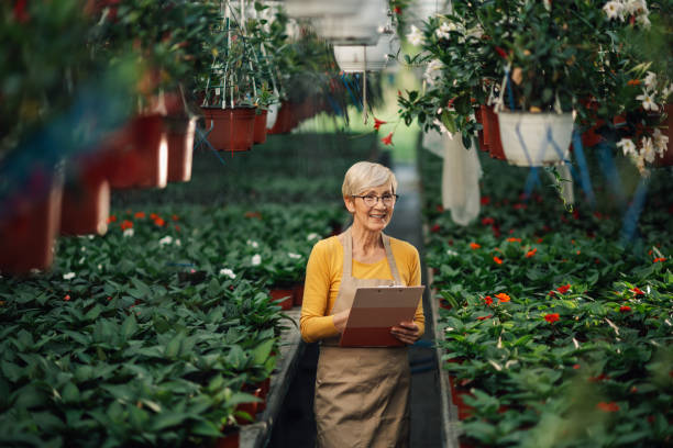 istock Happy old florist with clipboard at hothouse tracking flower growth. 2200186338