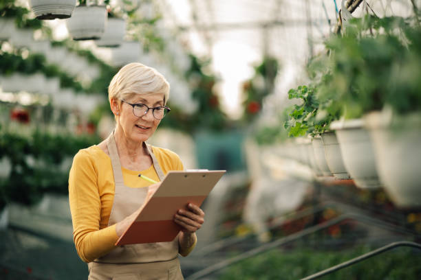 istock Close up of old botanist writing in clipboard while standing at hothouse 2200186365