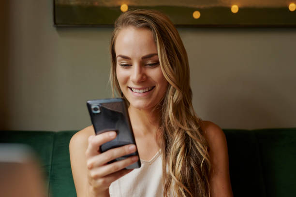 istock Woman, smartphone and happy at coffee shop for remote work, texting or notification on break, contact and chat. Person, copywriter and smile with phone, laptop or mobile app with project at cafeteria 2200186809