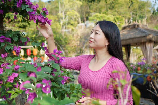 istock Asian woman admiring flowers 2200188380