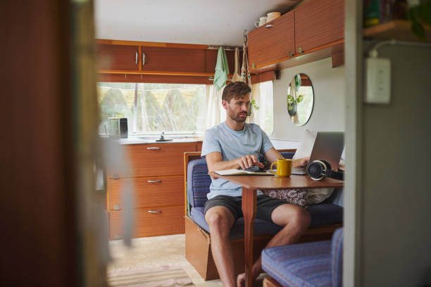 istock Caravan, man and connection with laptop for online, coffee and remote work for journalist on trip. Motorhome, male person and blog writer with digital for freelance, news story and tea cup in morning 2200188538