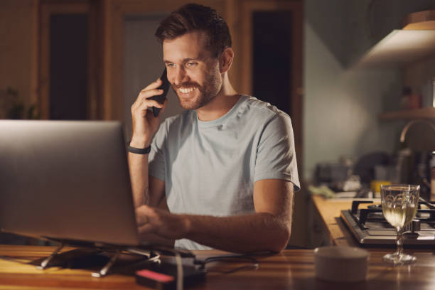 istock Remote work, phone call and smile with man and laptop for virtual consulting, it troubleshoot or update system. Network administrator, freelancer or night shift with person at home for client contact 2200189097
