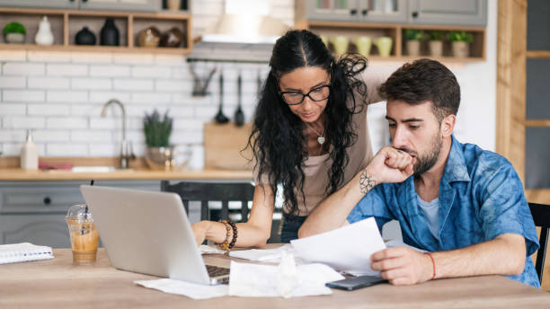 istock Couple calculating bills at home using tablet and calculator. 2200189429