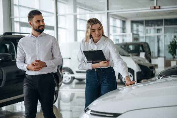 Black notepad in hands. Man and woman are in the car dealership stock photo