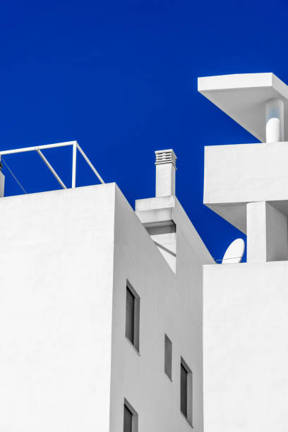 A glimpse from below of imposing blocks of white marble against a deep and clear blue sky.