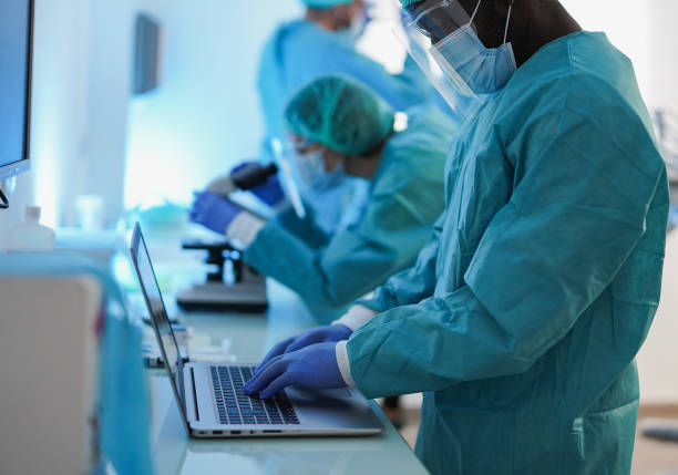 istock Multiracial medical workers with laptop computer and microscope inside hospital lab during virus outbreak - Virologie and laboratory concept - Focus on african man hand 2200191165