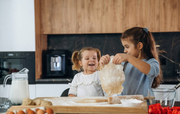istock Dough work. Two little girls are preparing bakery at home 2200191451