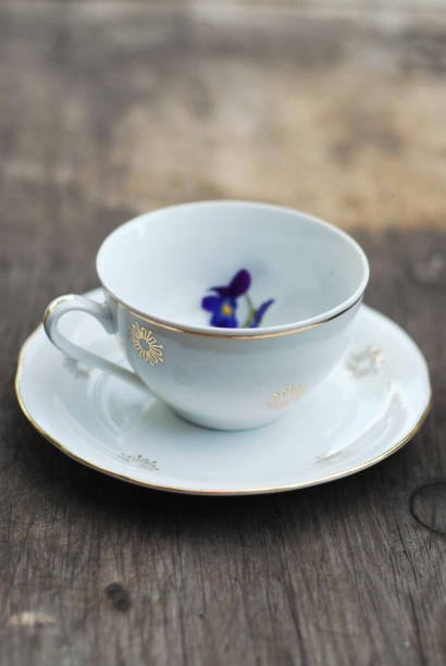 Vintage porcelain teacup with floral decoration on rustic wooden table