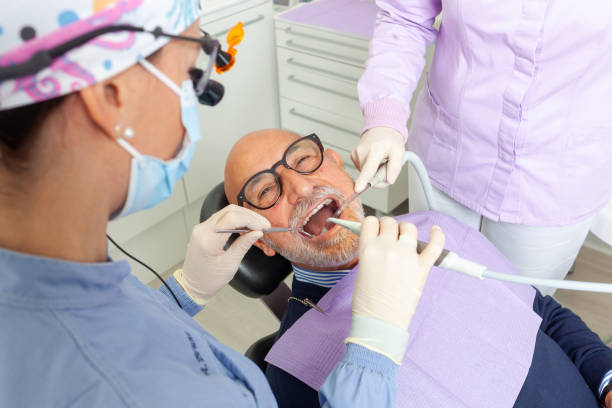 istock Dentist and assistant performing dental checkup on senior man 2200192625