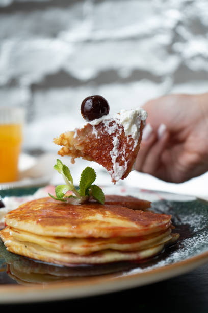 Pancakes with maple syrup, cream and black cherry on a bar table