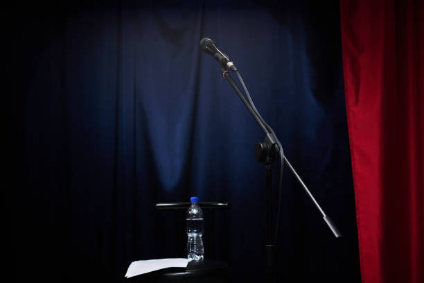 istock Microphone on Stand With Water Bottle on Dark Stage 2200195903