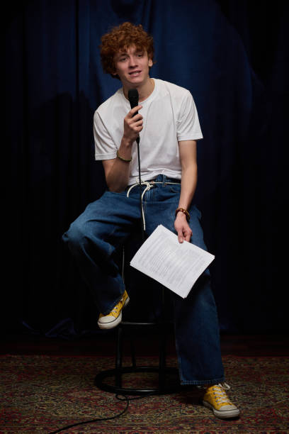 istock Young Man Singing into Microphone Holding Paper 2200195945