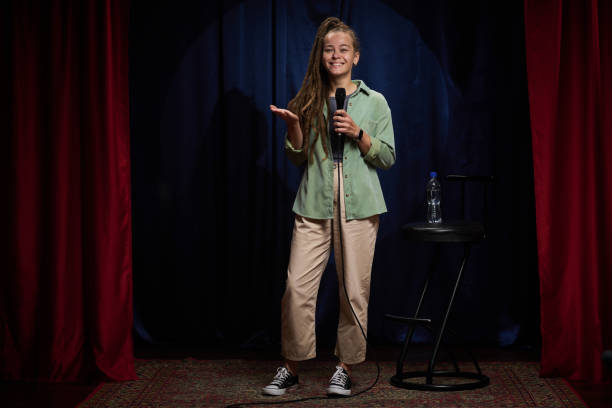 istock Smiling Girl Giving Stand-Up Comedy Performance on Stage 2200195957