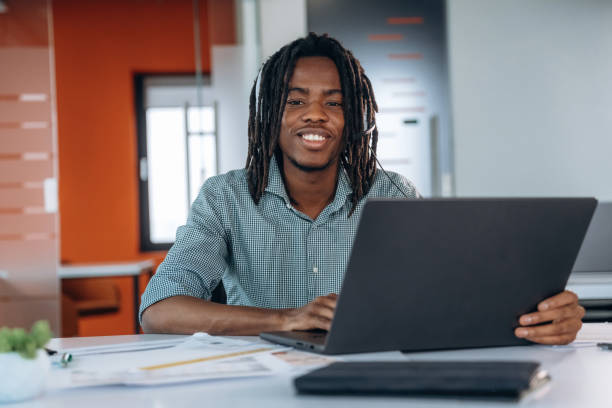 istock Smiling, sitting by laptop. Black businessman is working in office 2200198355