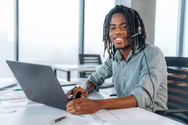 istock Smiling, sitting by laptop. Black businessman is working in office 2200198376