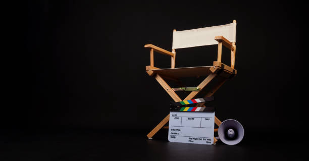 istock White director chair with clapper board and megaphone on black background. 2200200248