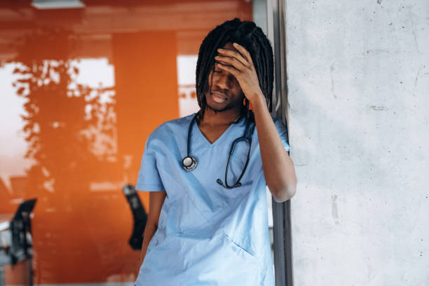 istock Headache, feeling bad, tired. Black man doctor is in the office 2200202612