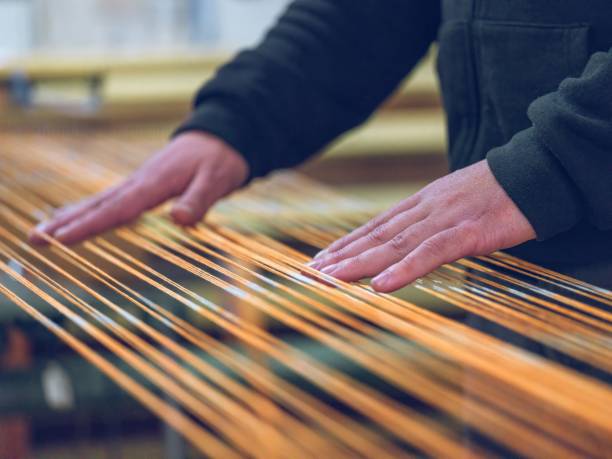 Hands working with yarn on industrial loom
