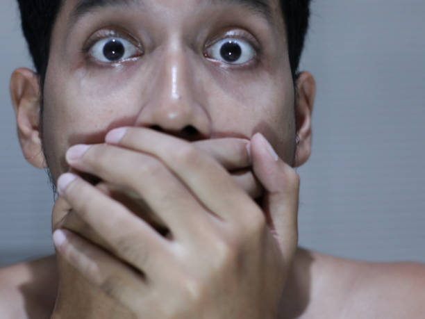 istock frightened asian man covering his mouth with both hands 2200203088