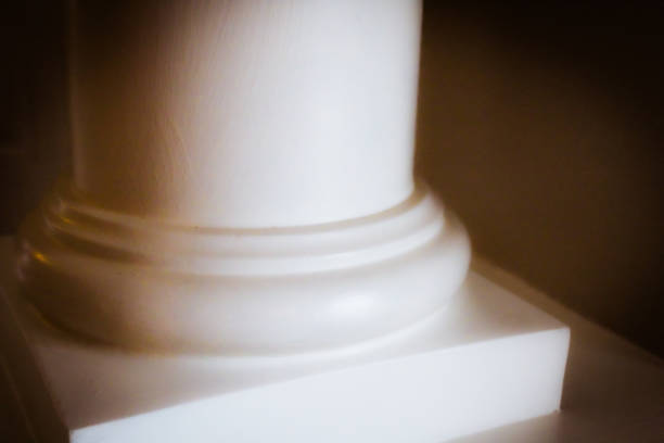 element of antique column in interior. photo zone for photo sessions. two white columns are located in interior. white chiffon fabric is planted.