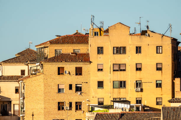 Warm sunlight illuminates a cluster of old buildings with red tile roofs in this European cityscape, showcasing classic architecture.