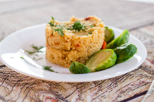homemade cooked bulgur with Brussel sprouts in a plate, on a wooden table .