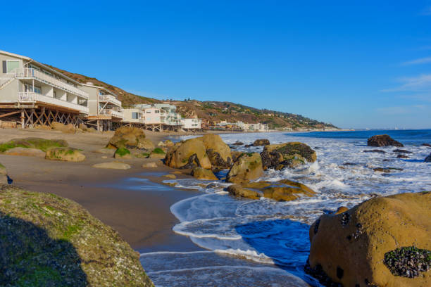 istock Waves Crashing on Rocks at Malibu Beach with Homes Behind 2200207034