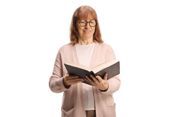 istock Elderly woman standing and reading a book 2200209209