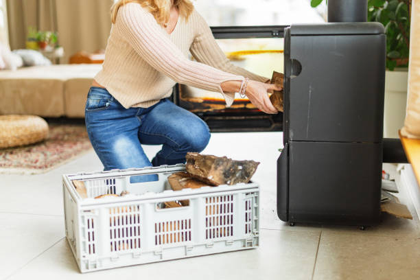 istock Woman Loading Firewood Into Indoor Stove 2200209361