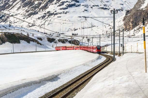 istock Red passenger train on a single-track railway running alongside a road across a high mountain pass in Switzerland 2200212890
