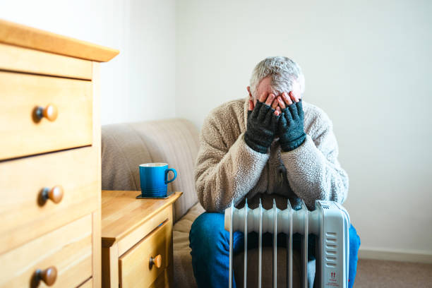 istock Cold worried man warming hands on electric heater at home 2200212976