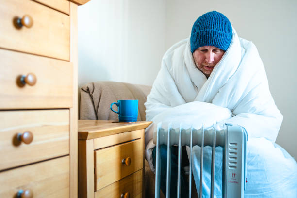 istock Cold worried man warming hands on electric heater at home 2200213167