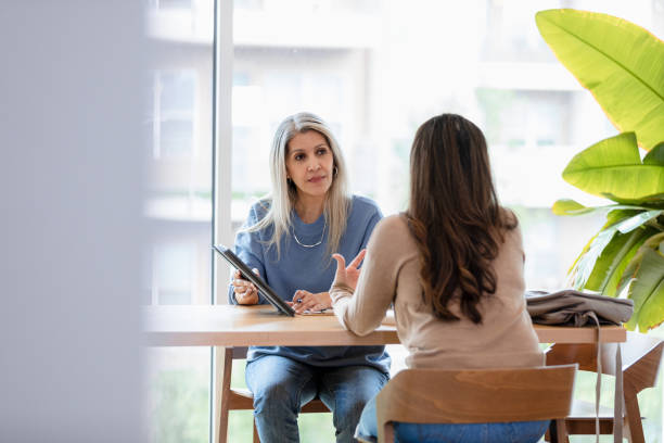 istock Mid Adult Woman Discussing Ideas with Colleague Using Tablet 2200217308