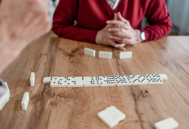 Senior husband and wife playing dominoes together at home