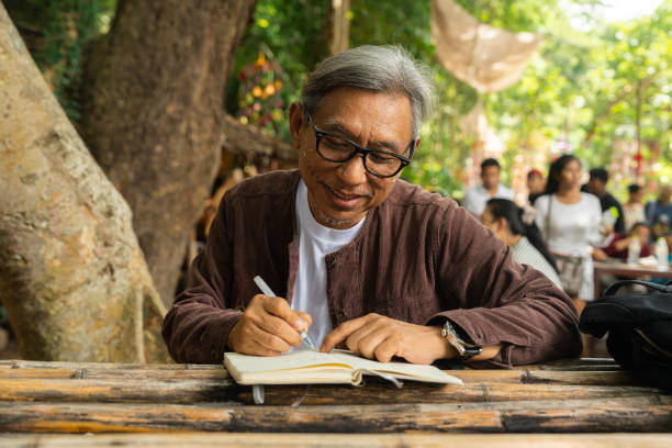 A senior man immersing himself in the nature during a vacation, finding fresh inspiration for writing his book