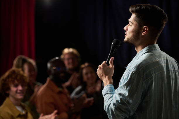 istock Man Singing on Stage in Front of Audience with Microphone 2200220308