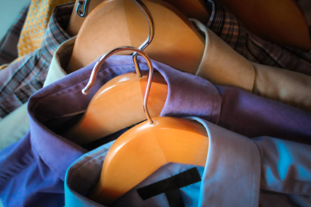 stylish display of long sleeve button down dress suit shirts. professional wardrobe on wooden hangers. macro close-up of clothing.