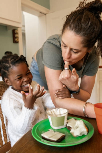 istock Mother and daughter having breakfast smiling at dining table 2200220657