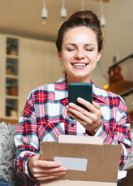 istock One-click ordering and same-day delivery concept. Woman sharing her online shopping experience using internet and smart phone. 2200224432